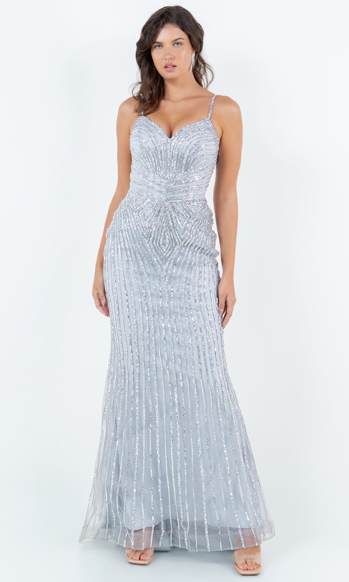 A woman models the Cinderella Couture 8268J long prom dress, featuring sparkly silver beading, thin straps, and a fitted sweetheart bodice, standing against a plain white background.